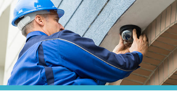 Engineer fitting a dome camera under the eaves
